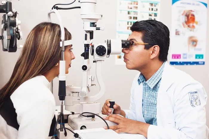 Consulta oftalmológica donde un especialista evalúa la salud ocular de una paciente que utiliza lentes de contacto, promoviendo el cuidado visual y la prevención de infecciones.