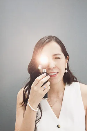 mujer en revision oftalmologica con luz directa, sonriendo durante consulta en clinica visual