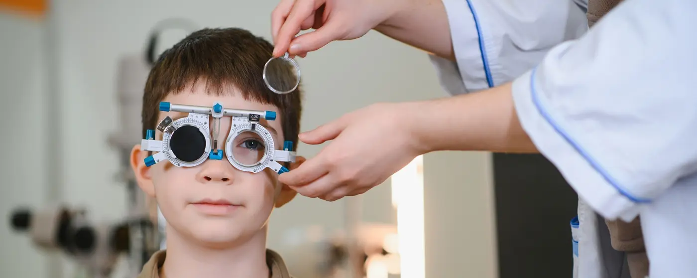 Niño durante un examen oftalmologico utilizando una montura de pruebas para evaluar astigmatismo y otros errores refractivos infantiles