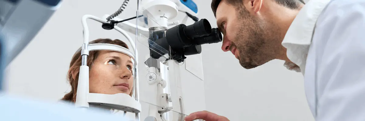 Profesional de salud examina el ojo de una paciente mediante una lámpara de hendidura durante una revisión oftalmológica.